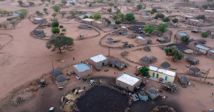 Aerial zoom out.  A typical farming village in the barren landscape of the Sahel region, Sahara Desert, Senegal. Drought, Climate Change, Desertification
