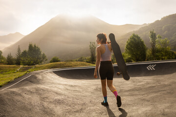 woman skating in skatepark at sunrise with longboard cap and short hair