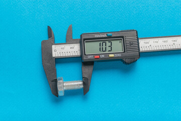 Measuring a metal bolt with an electronic vernier caliper on a blue background.