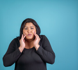 Hispanic woman holding her hands to her face in pain. TMJ concept