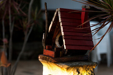 Casa de passarinho construída de madeira com porta em forma de circulo.  