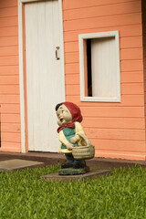 Anal de jardim na frente de uma casa de madeira de paredes cor de rosa e porta e janela branca. 