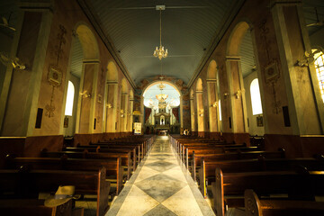 Igreja católica com bancos de madeira, portas em forma de arco, lustres, altar, piso de mármore e...