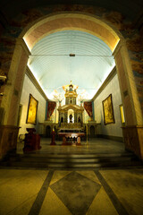 Interior de Igreja católica com porta em forma de arco, altar, imagens de santos, quadros, piso de...