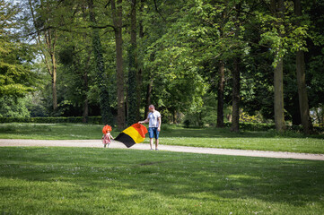 Portrait of a father with his daughter and the Belgian flag in the park.