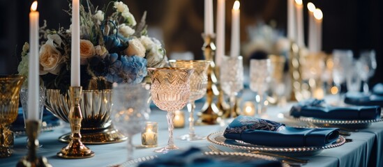 Fototapeta na wymiar A banquet table adorned with an opulent display of candles, plates, and luxurious decor. The setting exudes elegance with gold and blue elements complementing the warm glow of the candles.