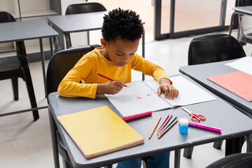 African American boy focused on drawing in a classroom setting