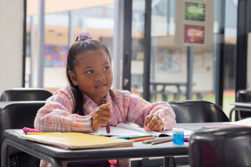 Biracial girl with a focused expression is writing in a notebook at school