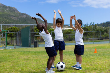 Three boys celebrate during a soccer game at school; two are biracial and one is African American