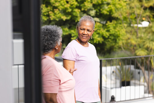 Senior African American woman converses with a senior biracial woman on a sunny balcony - Powered by Adobe