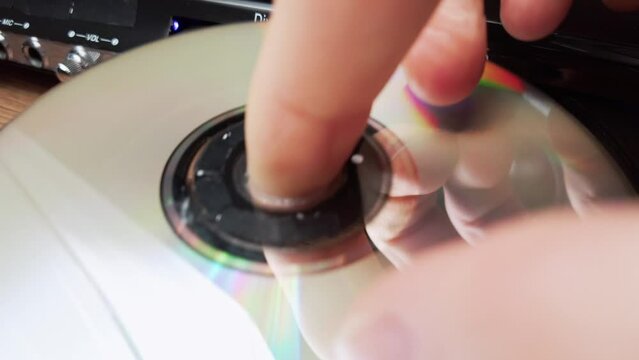 Loading compact disc into the DVD CD Player. Male hand loads CD into a CD player tray close-up. Music, movies, or data recorded on a laser optical information storage medium. Loading Compact Disc