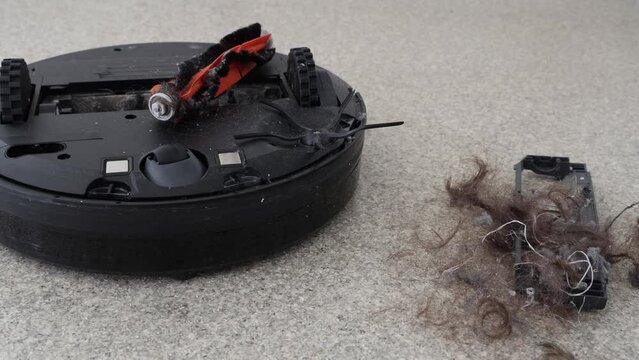 Pile of tangled hair and dust next to robot vacuum