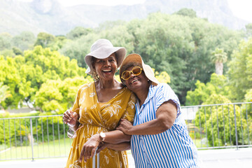 Senior African American woman and senior biracial woman share a joyful embrace outdoors on vacation