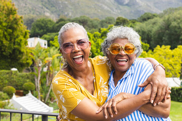 Naklejka premium Senior African American woman and senior biracial woman share a joyful embrace outdoors