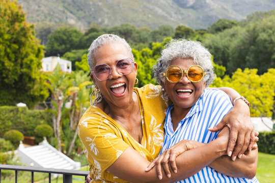 Senior African American woman and senior biracial woman share a joyful embrace outdoors