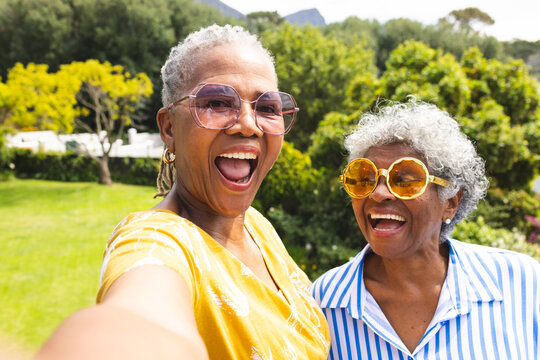 Senior African American woman and senior biracial woman share a joyful moment outdoors