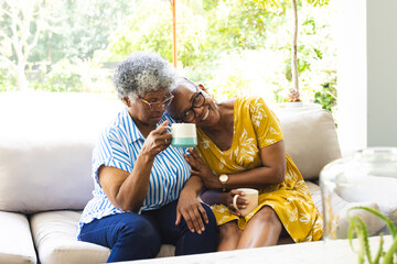 Obraz premium Senior African American woman and senior biracial woman share a cozy moment with coffee at home