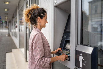 woman using credit card and withdrawing cash at the ATM