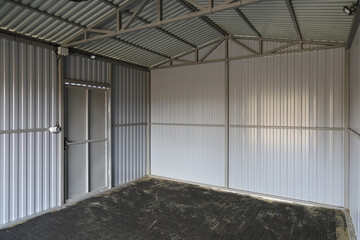 Interior of new empty iron garage, textured surface road tile on the ground, door in wall, Film...