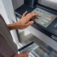 hands of woman using credit card and withdrawing cash at the ATM