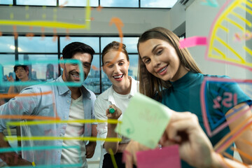 Skilled project manager pointing at glass wall while coworker thinking about plan. Diverse business team working together, brainstorming marketing idea or business plan. Creative start up. Tracery.