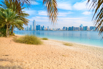 View from a sandy beach at Marina Mall island of the waterfront corniche and downtown skyline at Abu Dhabi, United Arab Emirates.