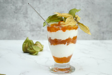 One glass jar of layered dessert with protein yoghurt and physalis fruit
