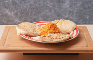 tempting spread of traditional cheese pupusas from El Salvador, served with curtido, atop a rustic red and white plate.