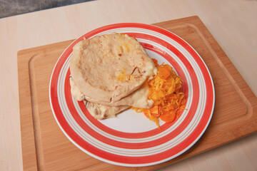 A savory trio of cheese pupusas, a staple of El Salvadoran cuisine, served with tangy curtido on a rustic platter.