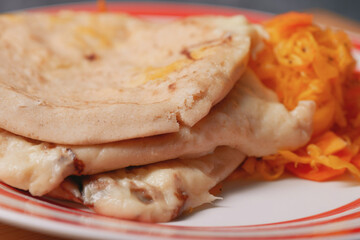 cheese pupusas on a rustic plate, complemented by vibrant curtido, emblematic of El Salvador's culinary heritage