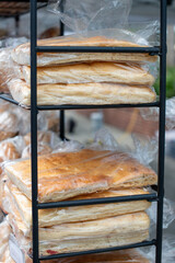 A stack of traditional Italian rosemary garlic focaccia bread on a black metal display. The airy...