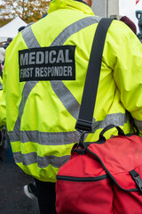 The back of a medical first responder wearing a bright yellow uniform coat with a grey reflective...
