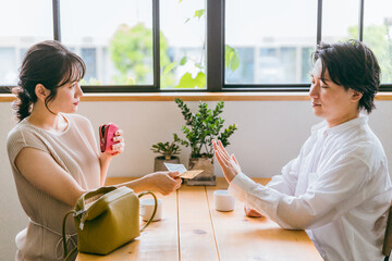 家のダイニングで会話する仲良しの若い日本人夫婦

