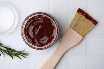 Marinade in jar, rosemary and basting brush on white tiled table, flat lay