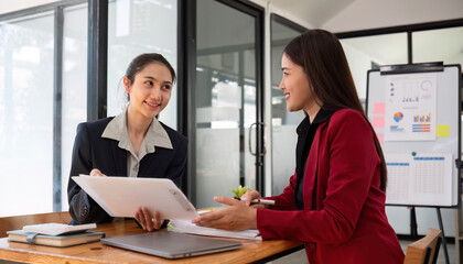Two businesswomen discussing project strategy in office conference room Businesswoman discusses project planning with colleagues in modern workplace, gives advice on financial data report