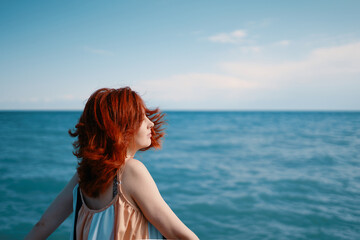 Captured against the vibrant blue sea, a young woman on the beach turns her head to look over her shoulder.