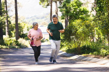 Senior biracial woman and biracial man jogging together in a park