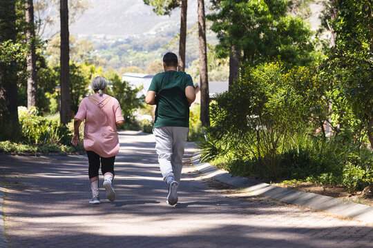 Senior biracial woman and biracial man jog together in a park