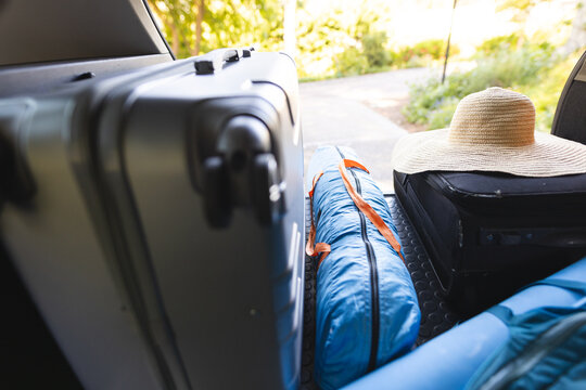 A car trunk is packed with luggage and a straw hat for a trip