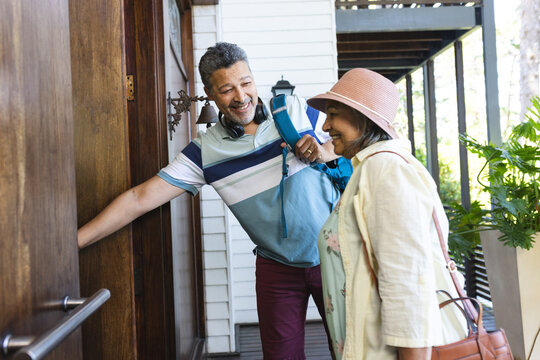 Senior biracial couple is smiling as the man opens a door for the woman