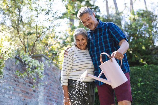 Senior biracial woman and biracial man share a joyful moment gardening outdoors - Powered by Adobe