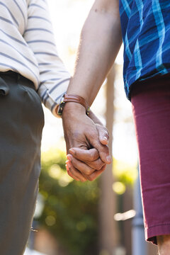 Senior biracial couple holding hands, showcasing a bond of affection