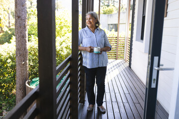 Senior biracial woman enjoys a serene moment with a cup of coffee on a balcony