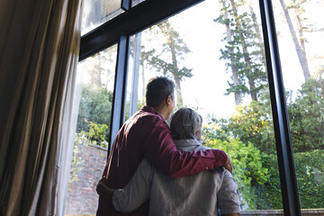 Senior biracial couple enjoys a serene view through a large window