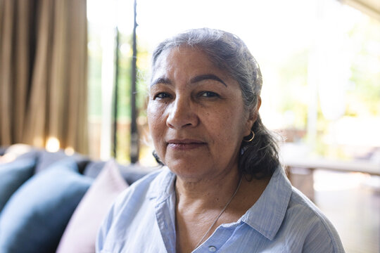 Senior biracial woman with grey hair and a gentle expression, wearing a blue shirt