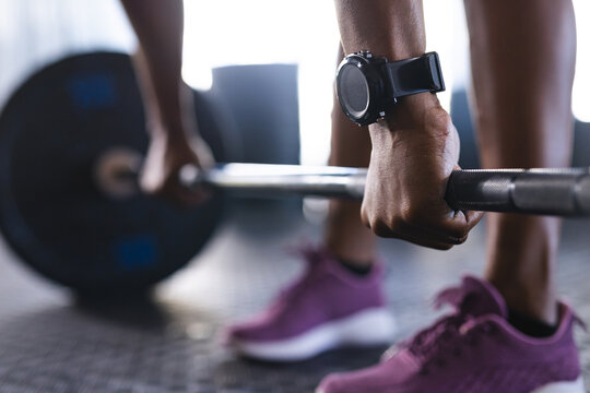Close-up of a person's hands gripping a barbell, wearing a fitness watch