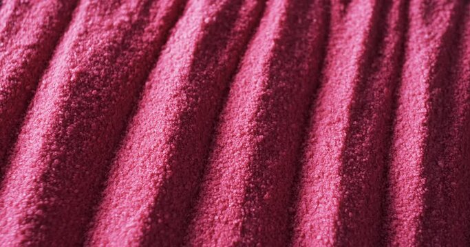 A close-up view of a textured pink fabric with distinct ridges