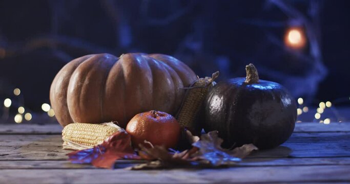 A festive autumn display features pumpkins and corn on a wooden table