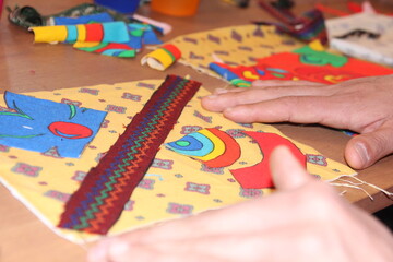 A person focused on cutting, folding and pasting construction paper to create a colorful and beautiful kite.