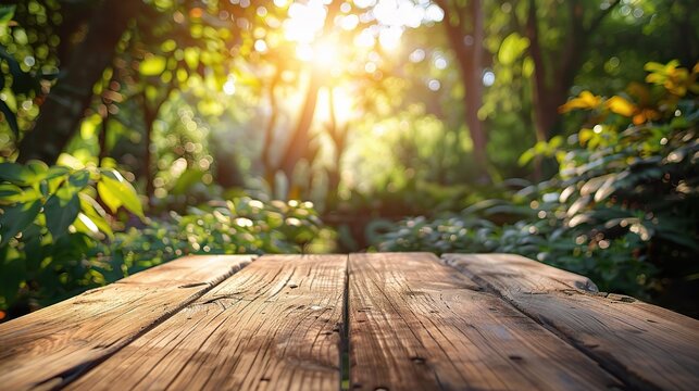 An empty wooden table top in focus with a beautifully blurred background of a lush green garden basking in sunlight